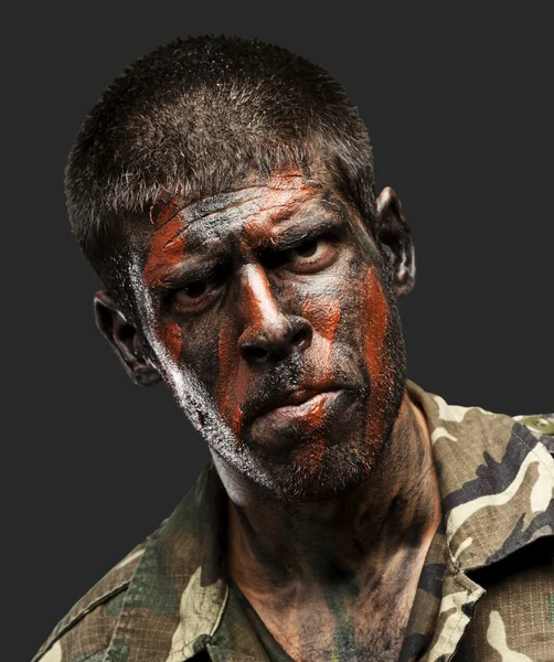 Jeune soldat avec la peinture de camouflage regardant très sérieux sur bl — Photo