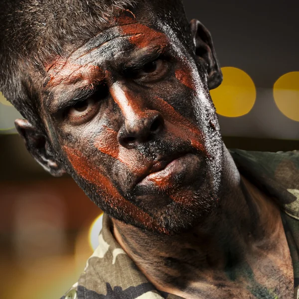 Young soldier with camouflage paint looking very serious at city — Stock Photo, Image