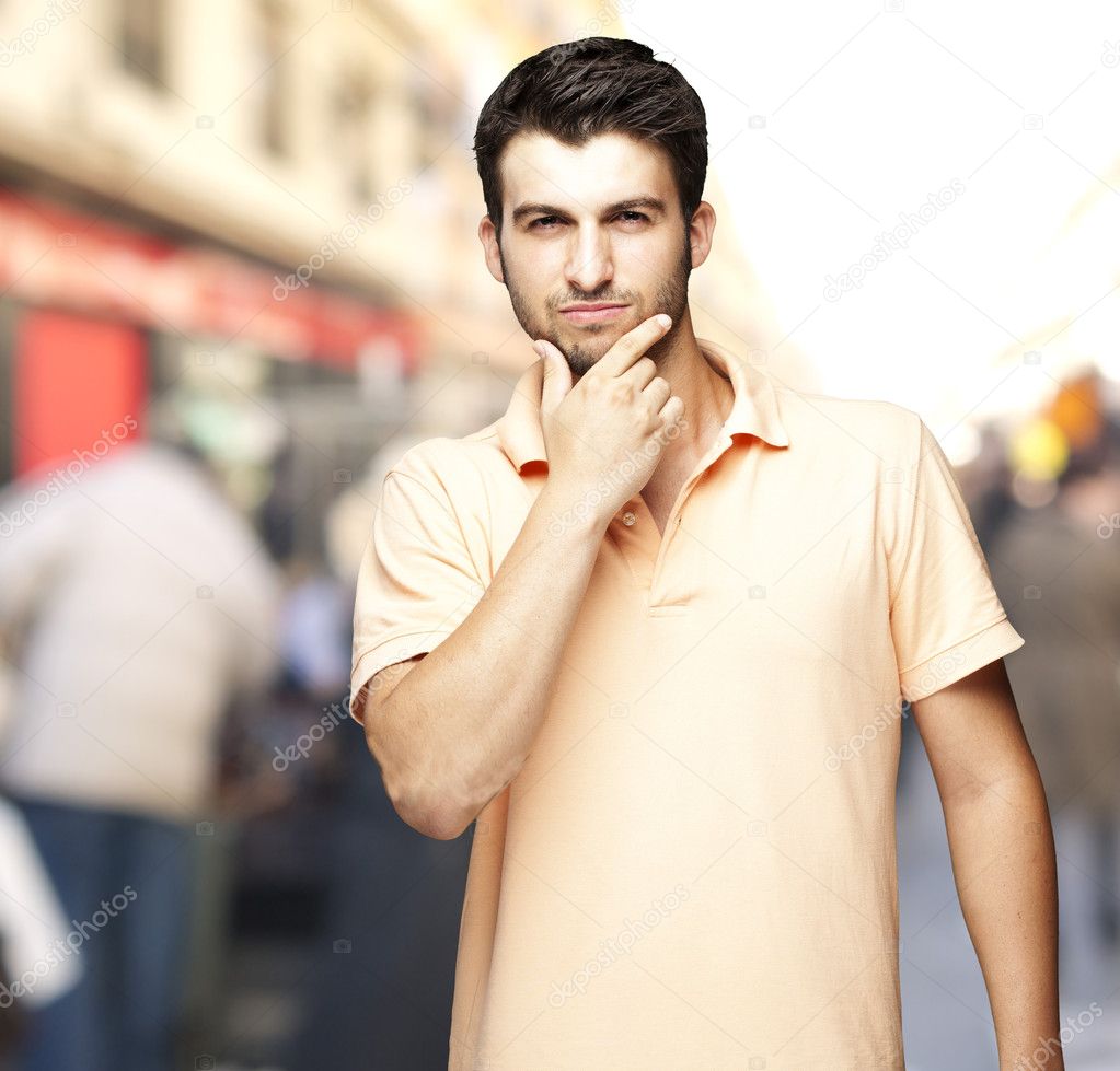 Portrait of a comely young man thinking at a crowded street