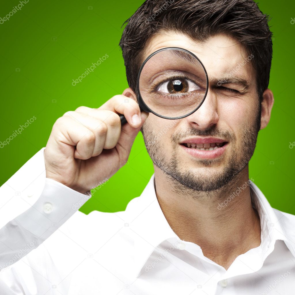 Portrait of young man looking through a magnifying glass