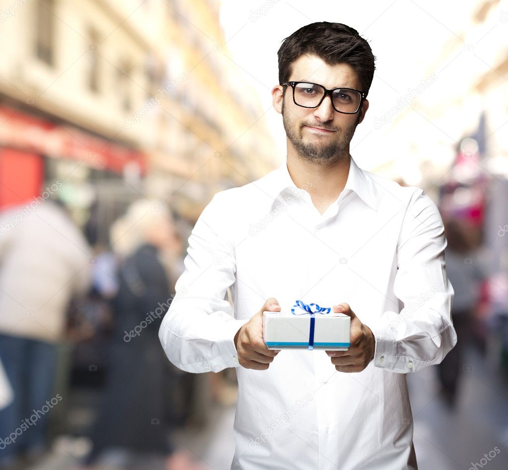 Portrait of young man offering a gift at city