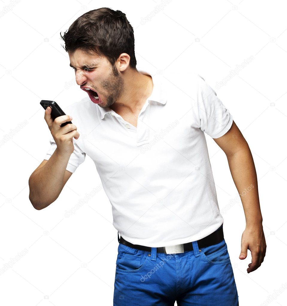 Portrait of angry young man shouting using mobile over white bac
