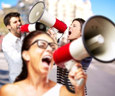 Young friends screaming with megaphone against a building clipart