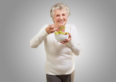 gri backgrou taze salata yiyen kadın kıdemli portresi