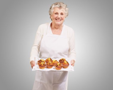 Portret van senior vrouw weergeven met een chocolade muffin lade bij het stre