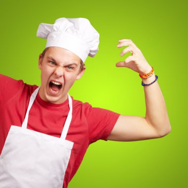 Portrait of young cook man wearing apron doing aggressive gestur clipart