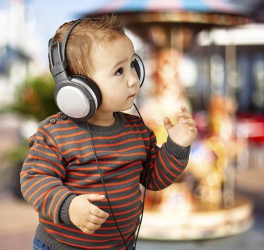 Portrait of adorable kid with headphones listening to music agai clipart