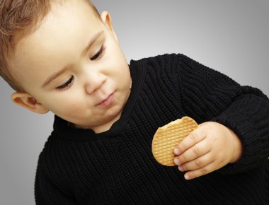 gri bir backgro karşı bisküvi yeme yakışıklı çocuk portresi
