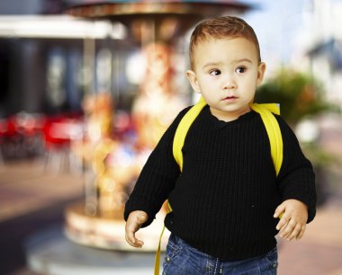 Portrait of adorable kid carrying yellow backpack against a caro clipart