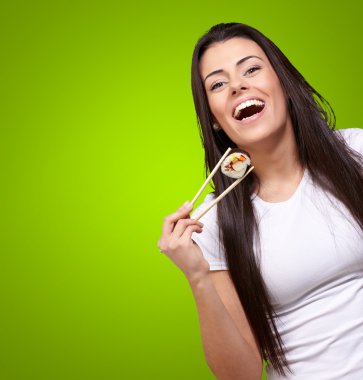 Portrait of young woman holding sushi against a green background clipart