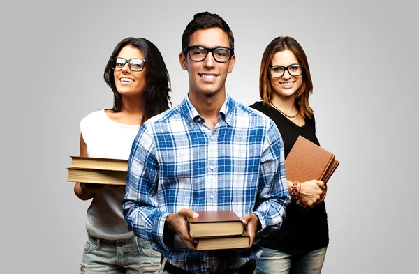Jóvenes estudiantes sosteniendo libros sobre fondo gris —  Fotos de Stock