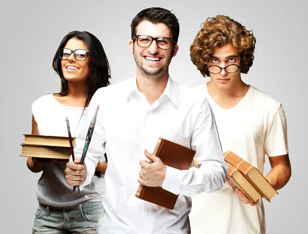 Portrait of young students holding books over grey background — Stock Photo, Image