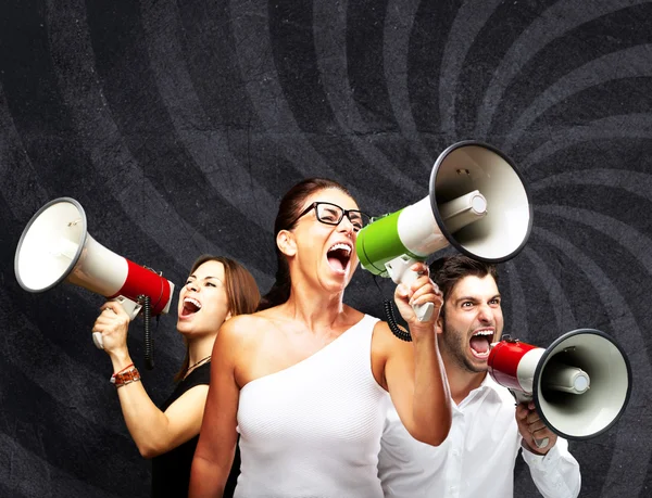 Shouting with megaphone against a grunge wall — Stock Photo, Image