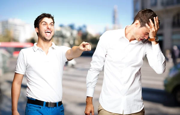 Young man pointing a guy and joking at city — Stock Photo, Image