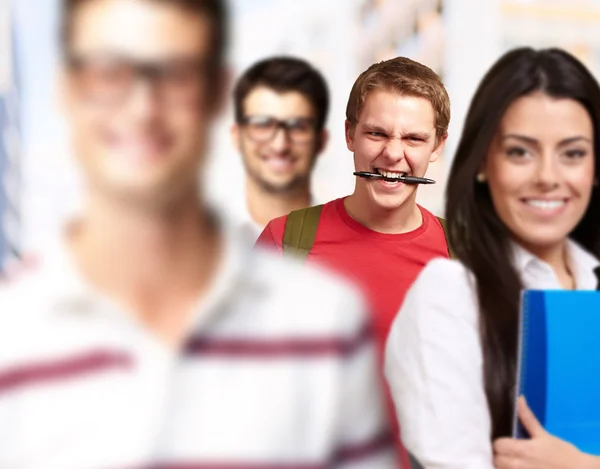 Young friends smiling and one biting a pen — Stock Photo, Image