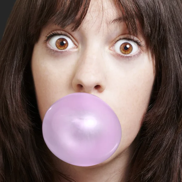 Young girl with a pink bubble of chewing gum against a black bac — Stock Photo, Image