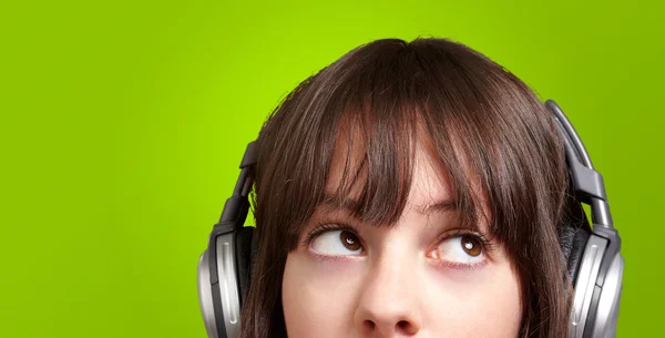Portrait of young woman listening to music over green — Stock Photo, Image
