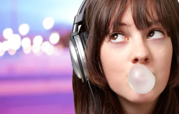 Porträt einer jungen Frau, die mit Kaugummi Musik hört — Stockfoto