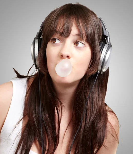 Porträtt av ung kvinna lyssna på musik med tuggummi över — Stockfoto