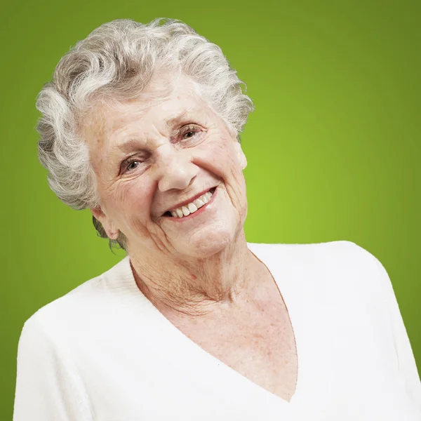 Vrij senior vrouw die lacht tegen een groene achtergrond — Stockfoto