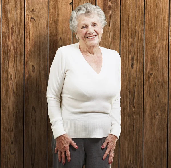 Pěkně starší žena s úsměvem dřevěné pozadí — Stock fotografie
