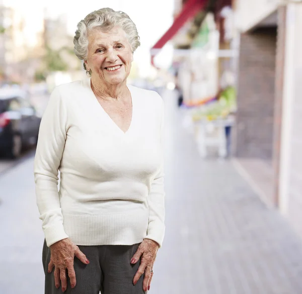 Симпатичная пожилая женщина улыбается на фоне улицы — стоковое фото