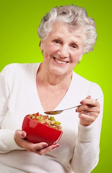 Ritratto di donna anziana che tiene una ciotola di cereali contro un verde — Foto Stock