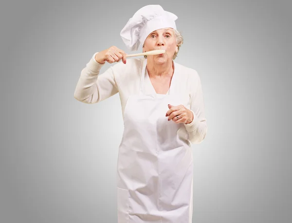 Retrato de cocinera mujer mayor con cuchara de madera en la boca más gr —  Fotos de Stock