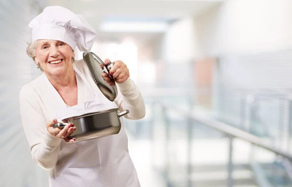 Porträtt av cook senior kvinna öppna kastrull på restaurang — Stockfoto