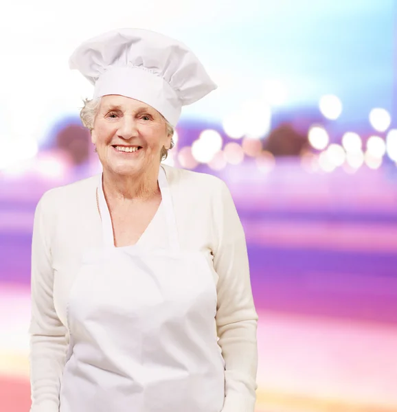 Retrato da cozinheira sênior mulher sorrindo contra um resumo — Fotografia de Stock
