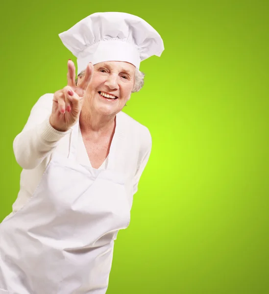 Портрет кухарки старшої жінки робить жест схвалення над зеленим — стокове фото