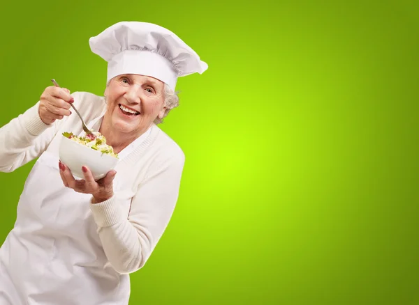 吃沙拉在绿色的高级厨师女人的画像 — 图库照片
