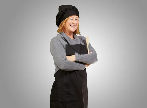 Retrato de mulher cozinheiro vestindo avental sobre fundo cinza — Fotografia de Stock