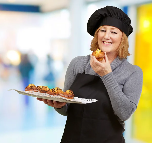 Portrét středního věku, kuchař žena drží domácí muffin ind — Stock fotografie