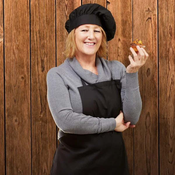 Πορτρέτο της μέσης ηλικίας μάγειρας γυναίκα που κρατά ένα σπιτικό muffin Αγά — Φωτογραφία Αρχείου