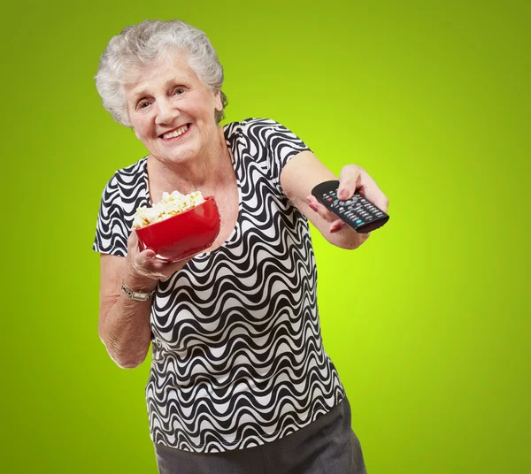 Portret szczęśliwy starszy kobieta patrząc w tv backgro zielony — Zdjęcie stockowe