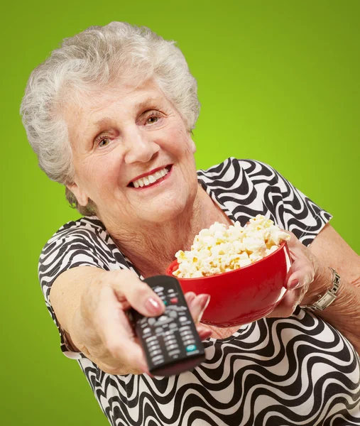 Portrait of senior woman holding pop corn bowl and changing chan — Stock Photo, Image