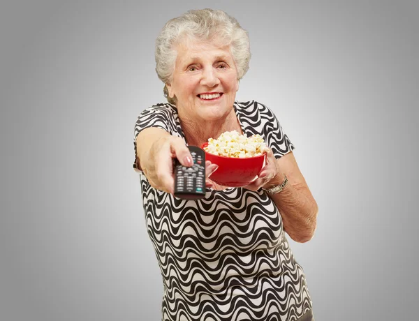 Portrait of senior woman holding pop corn bowl and changing chan