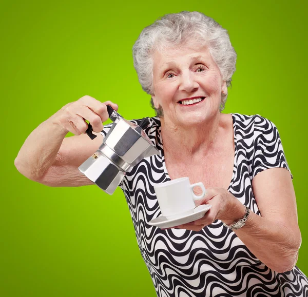 Portrait of a vitality senior woman serving a tea cup over green — Stock Photo, Image