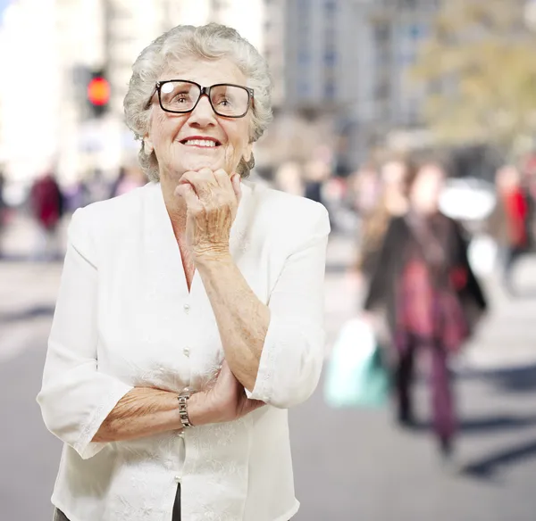 Porträt einer Seniorin, die denkt und auf ein überfülltes Haus blickt — Stockfoto