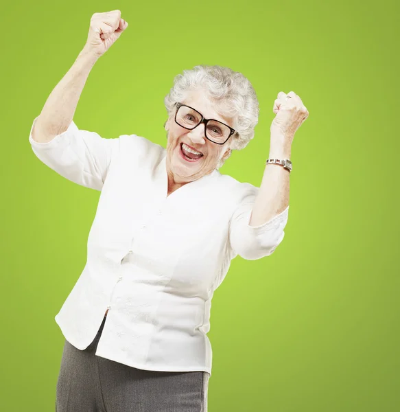 Retrato de uma mulher idosa alegre gesticulando vitória sobre o verde — Fotografia de Stock