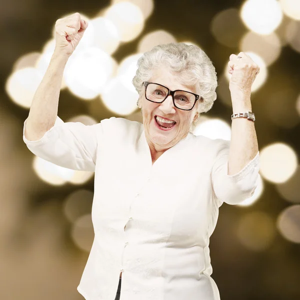 Retrato de uma mulher idosa alegre gesticulando vitória contra um — Fotografia de Stock