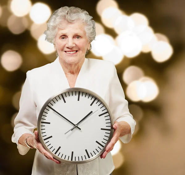 Portret szczęśliwą kobietą starszy zegar gospodarstwa przed abstrac — Zdjęcie stockowe