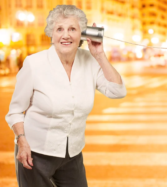 Porträt einer Seniorin, die nachts mit Blech hört — Stockfoto