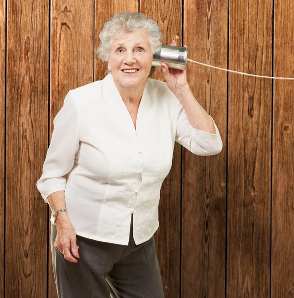 Ritratto di donna anziana udente con lattina di metallo contro un wo — Foto Stock