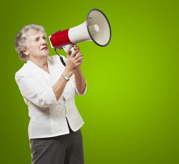 Портрет пожилой женщины, держащей мегафон на зеленом фоне — стоковое фото