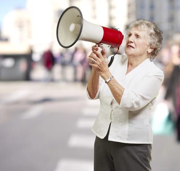 Retrato de mujer mayor sosteniendo megáfono en la ciudad — Foto de Stock