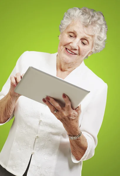 Portrait of senior woman touching digital tablet over green back — Stock Photo, Image