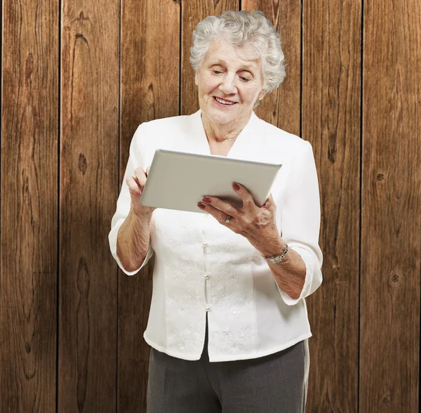 Portrét starší ženy dotýká digitálním tabletu proti zalesněný — Stock fotografie