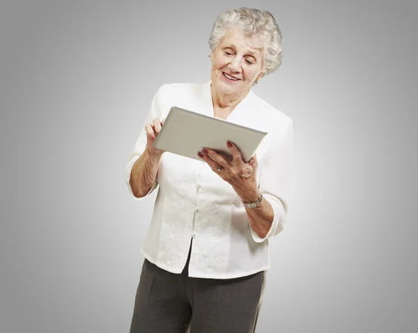 Porträtt av äldre kvinna röra digital tablet över grå backg — Stockfoto